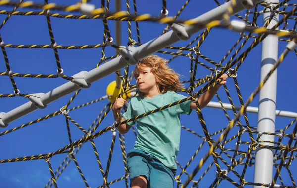 Little kid boy hanging on the monkey bar by his hand to exercise at outdoor playground. Rope Park. — Stock Photo, Image