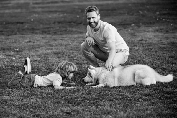 笑着的父亲和他的儿子在公园里和狗玩耍,和宠物玩耍.男孩带着小狗散步. — 图库照片