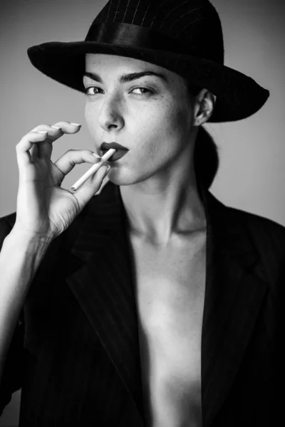 Mulher sexy com lábios vermelhos fumando. Feminino de terno preto . — Fotografia de Stock