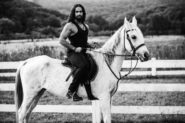 Homem montando cavalo. Um cowboy giro. Jovem musculoso de t-shirt a cavalo. Sexy torso masculino. — Fotografia de Stock
