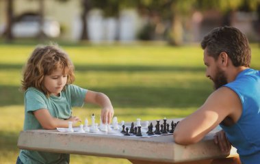 Baba ve oğul satranç oynuyor. Babalar Günü, aileyi sevmek, ebeveynlik, çocukluk konsepti. Çocuklar için oyunlar ve aktiviteler. Konsantre çocuk ailesiyle masa oyunu oynayarak satranç stratejisi geliştiriyor..