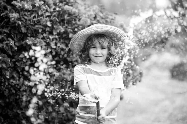 Hasır şapkalı şirin çocuk hortumla gülüyor.. — Stok fotoğraf