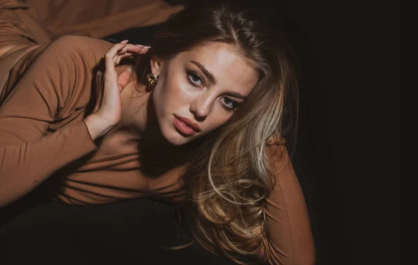 Jonge vrouw poseert in de studio over zwarte achtergrond. Sexy meisje in sensuele verleidelijke pose op zwarte studio. Fashion portret van mooie vrouw met donker licht op gezicht. — Stockfoto