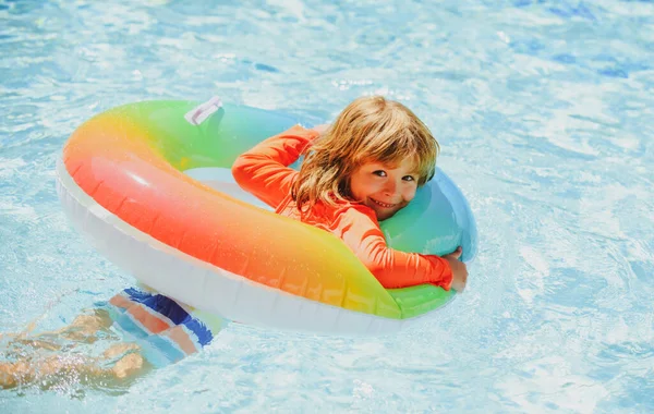 Ребёнок в летнем бассейне. Летние каникулы. Летние детские выходные. Мальчик в бассейне. Мальчик в аквапарке на надувном резиновом круге. — стоковое фото
