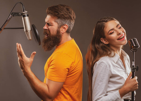 Happy couple in recording studio. Music performance vocal. Singer singing song with a microphone.