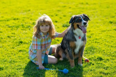 Parkta evcil köpeği olan küçük bir çocuk. Yavru köpeği olan sevimli bir çocuk, açık hava yazı. Mutlu bir çocukluk. Komik köpek..