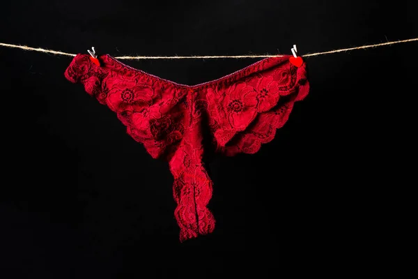 Vrouwen erotische rode ondergoed slipje opknoping aan touw geïsoleerd op zwarte achtergrond. Kant lingerie, vrouw sexy ondergoed. — Stockfoto