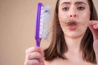 Saç dökülmesi. Kadın saç dökülmesinden rahatsız. Sorunlu saçlı, izole edilmiş üzgün bir kızın portresi. Endişeli kız uzun hasarlı, sağlıksız saçları elinde tutuyor..