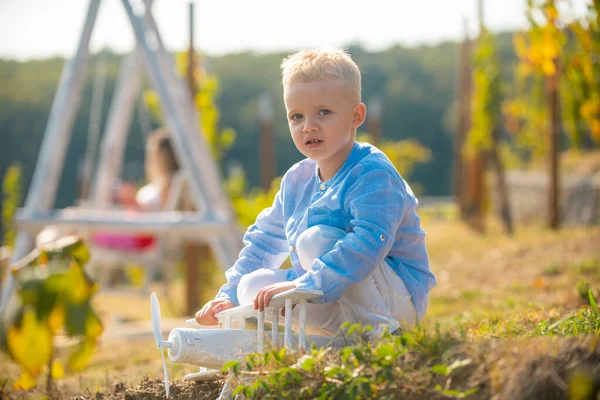 Barn som har kul med leksak flygplan i fält mot naturen bakgrund. Äventyr och semester barn koncept. Sommar på landet. Drömmar om flygning. Sommar på landsbygden. — Stockfoto