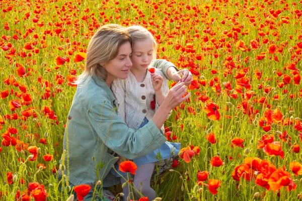 Frohe Frühlingsfamilie. Schöne Kind Mädchen mit junger Mutter tragen lässige Kleidung in Feld von Mohnblumen. Familie auf Frühlingsmohnfeld. — Stockfoto