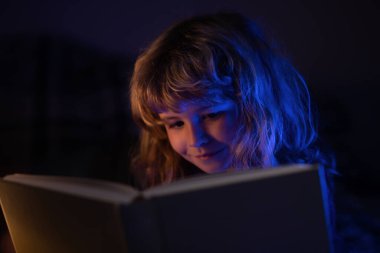 Kitap okuyan şirin bir çocuk. Açık kitabı olan bir çocuk. Ev okulu dersi. Evde kitap okumaya odaklanmış küçük bir çocuk. Mutlu çocukluk, rüya çocuk.