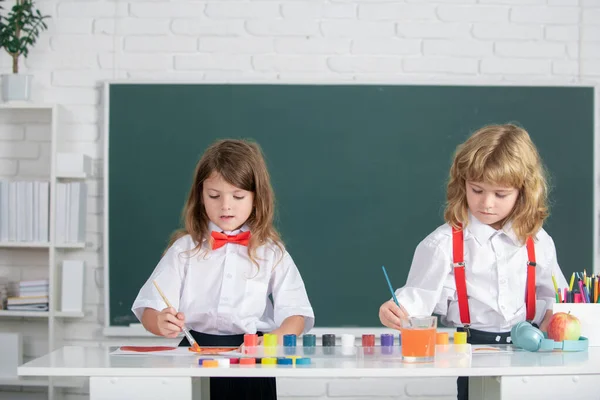 Skolbarn flicka och pojke målning med färger färg och pensel i klassrummet. Barn konst, kreativitet barn koncept. — Stockfoto