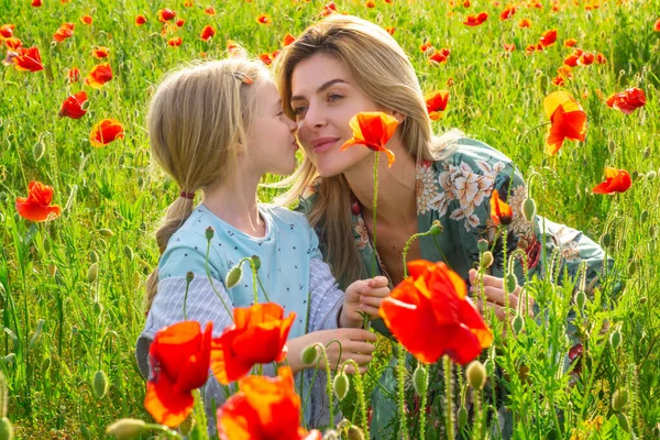 Η μαμά με ένα κοριτσάκι σε ένα χωράφι με κόκκινες παπαρούνες απολαμβάνει τη φύση. Μητέρα και μικρή κόρη στο χωράφι με τις παπαρούνες. Μια νεαρή γυναίκα με την κόρη της σε ένα χωράφι με παπαρούνες. Σχεδιασμός ελατηρίου. — Φωτογραφία Αρχείου