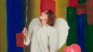 Sarışın, kıvırcık saçlı, elinde kameraya poz veren kırmızı balonlar tutan çekici melek kız. Tatil partisi. Neşeli model eğleniyor..