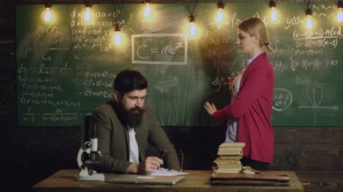 Sınıfta profesörü dinleyen lise öğrencisi. Öğretmen açıklama matematiği. Tahtada profesörlerin takım çalışması tartışması. Profesör yetişkin öğrencilere eğitim konsepti öğretiyor.