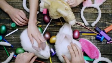 Paskalya yumurtalarını aile eliyle boyamak. Paskalya tavşanı ve paskalya yumurtası ahşap masa.