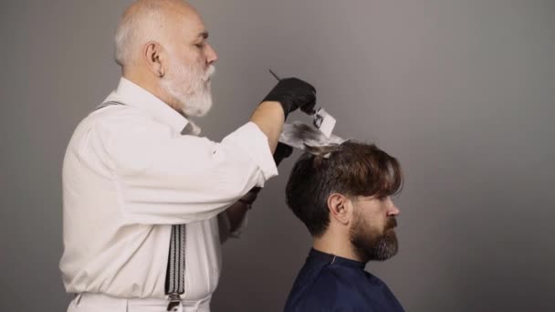 Kuaför erkek saçı ölüyor. Erkek saç boyama işlemi. Fırça kullanırken saçını boyayan bir adam. Berber salonunda gri saç boyası. Saç bakımı ve kuaförlük yapan erkekler. — Stok video