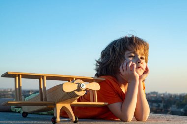 Çocuklar dışarıda klasik ahşap uçakla oynuyorlar. 6 yaşındaki çocukların portresi yaz gökyüzü arka planına karşı. Seyahat ve özgürlük kavramı.