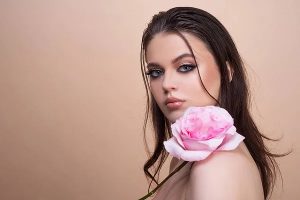 Красивое женское лицо и цветок. Девочка и розовая роза. Крупный план портрет, уход за кожей, макияж. — стоковое фото