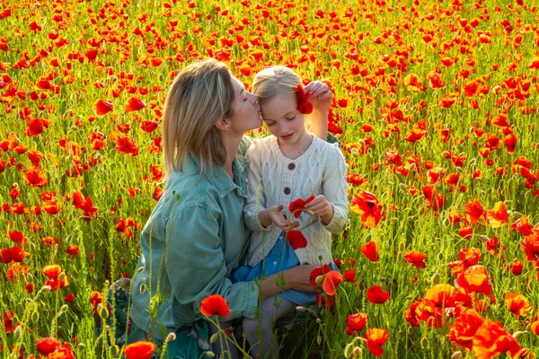 Mutter mit Tochter im Freien im Mohnfeld. Mutter umarmt liebes Kind auf Mohnblumen Hintergrund. Familie auf dem Feld der Frühjahrsblütenwiese. Mutter und Tochter im Frühling. — Stockfoto