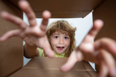 10 yaşındaki çocuk kutusunu açar ve içinden hediyesini çıkarır. Küçük çocuk paket kutusuna bakıyor ve bir sürpriz aldığına seviniyor. Çocuk, hediyesini el ile aç..