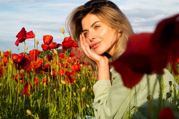 Красивая молодая женщина на маковом поле. Счастливая женщина отдыхает на красивом маковом поле. Девушка веселится весной на открытом воздухе. Женщина в поле с красными маками. — стоковое фото