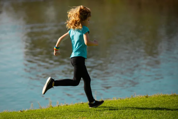 Kinderläufer laufen auf dem Rasen im Park. Kind läuft im Freien. Gesunde sportliche Aktivität für Kinder. Kleiner Junge beim Leichtathletik-Wettkampf. Outdoor-Sport und Fitness für Kinder, Bewegung im Freien. — Stockfoto