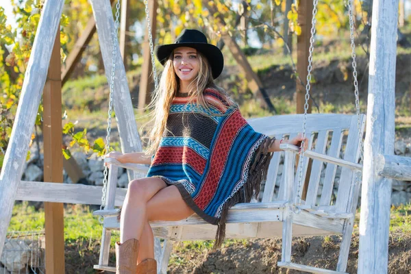 Şapkalı seksi kadın yaz parkı bahçesinde salıncakta sallanıyor. Dinlenme odasında dinlenen şehvetli sarışın kız. Hippi kız..