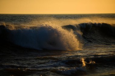Deniz dalgaları arka planı. Tropikal denizin üzerinde sahil gündoğumu. Sahilde dalgaların sıçradığı renkli bir gün batımı..
