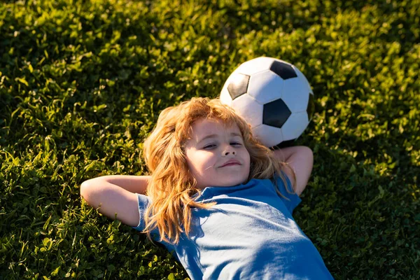 Piłkarz marzący, leżący na trawie. Młody piłkarz. Sport dla dzieci. Marzenie dzieci relaks na świeżym powietrzu. — Zdjęcie stockowe