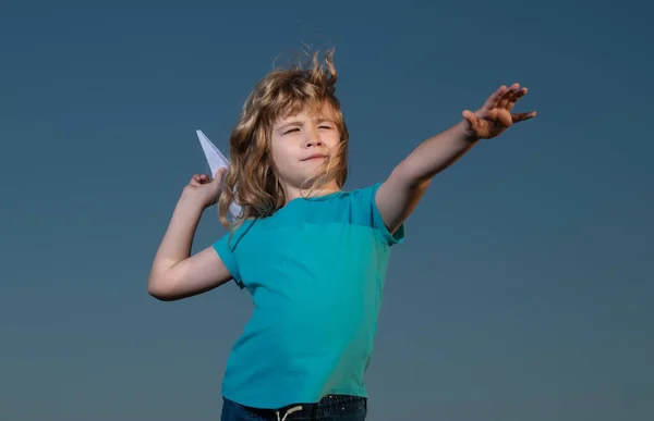 Jongetje gooit een papieren vliegtuig met blauwe lucht achtergrond. — Stockfoto