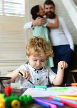 Üç kişilik mutlu bir aile birlikte eğleniyor, resim çiziyor. Neşeli ebeveynler oğluyla oynuyor. Çocuk resim öğreniyor, ressam resmi yapıyor, resim çiziyor. Baba ve çocuk evde birlikte oynuyorlar..