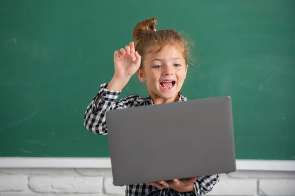 Menina estudante animado usando computador portátil na aula da escola no quadro negro. — Fotografia de Stock