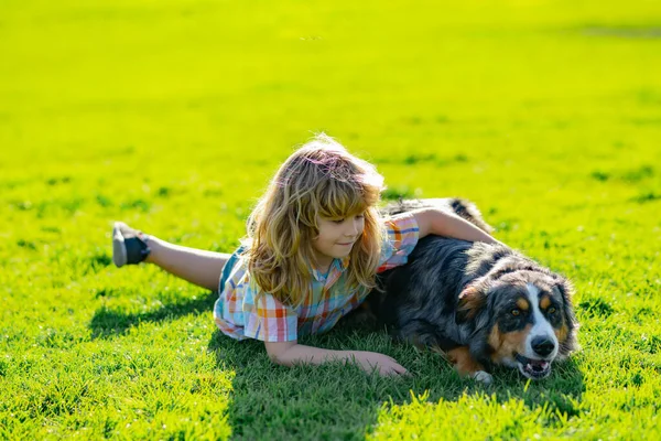 Niño abrazando a un perro al aire libre. El niño abraza cariñosamente a su perro mascota. Lindo niño con un perro cachorro, verano al aire libre. —  Fotos de Stock
