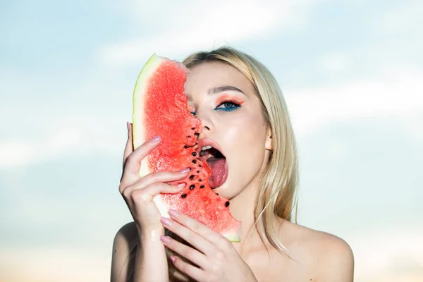 Sensuell ung kvinna slickar vattenmelon med sexig tunga. Sommarsmak. Glada ung kvinna som håller del av vattenmelon mot halva ansiktet och slickar vattenmelon. — Stockfoto