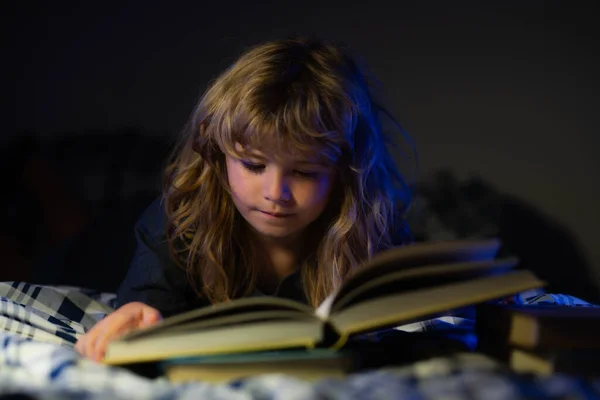 Criança lendo um livro na cama antes de ir dormir. Menino deitado na cama a ler livros em casa. História de dormir, crianças conto de fadas. — Fotografia de Stock