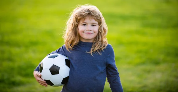 Młody piłkarz w odzieży sportowej z piłką nożną. Wesoły chłopiec cieszyć się piłką nożną, mecze sportowe piłki nożnej. Dzieciak trzyma piłkę, portret dzieci z bliska. Portret chłopca trzyma piłkę nożną. — Zdjęcie stockowe