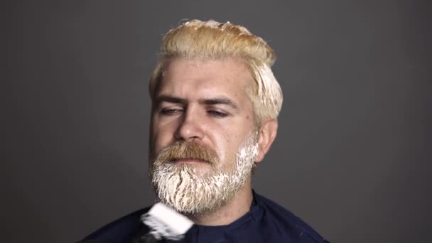 理发师正在垂死的男性头发。男人用刷子染发.理发师把一个留胡子的男人的胡子染成了染料.理发店灰白头发的颜色。美发和男性发型师. — 图库视频影像