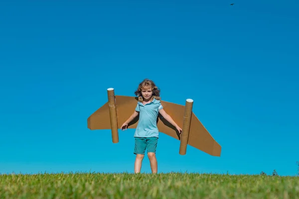 Kinderfantasie, Kinderpilot mit Papierflügeln, der sich im Freien vergnügt. Sommerurlaub und Reisekonzept. — Stockfoto