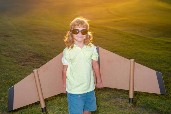 Barn med pilotglasögon som flyger i flygplan tillverkade av papp vingar. Dröm, fantasi, barndom. Resor och sommar semester koncept. — Stockfoto