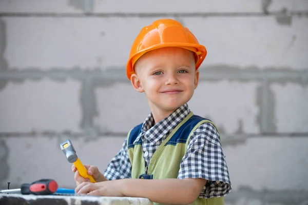 Schattig klein kind in bouwhelm met reparatie gereedschap op de bouwplaats. Een jongen in een bouwhelm die hard werkt. Gelukkig lachende kinderen onderwijs en carrière. Kinderen bouwer en reparatie. — Stockfoto