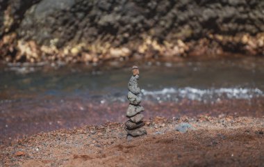 Sahilde bir çakıl taşını dengelemek, uyum ve denge kavramı. Taşlar dengeleniyor.