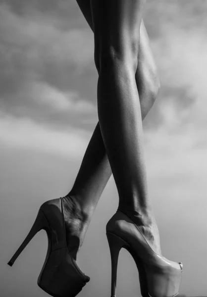 Mode foto av vackra eleganta kvinnliga ben med klackar. Kvinnliga ben med svarta höga klackar på himlen bakgrund. — Stockfoto