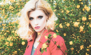 Sarışın, yüksek moda mankeni bir kız. Canlı Makyaj. Çiçek tarlası olan güzel bir model kadın. Bahar çiçekleri açan güzel kadın..