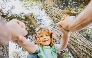 Mutlu çocuk yaz zamanı ağaca tırmanıyor. Baba eli..