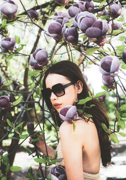 Ritratto di modello di bellezza con occhiali da sole. Donna caucasica modella posa all'aperto. Primavera Moda modella donna posa su Magnolia fiori sfondo . — Foto Stock