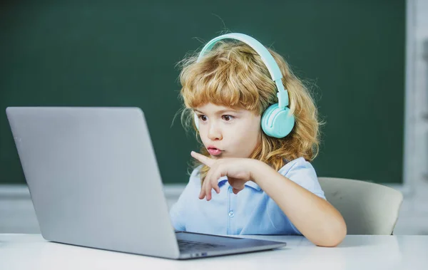 Schoolkinderen met laptop en koptelefoon in de klas op school. — Stockfoto