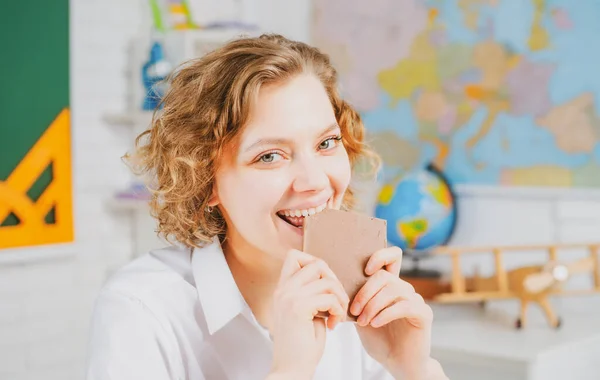Το πορτραίτο μιας φοιτήτριας. Νέος δάσκαλος ή δάσκαλος τρώνε σοκολάτα στην τάξη στο σχολείο. Εκπαίδευση των γυναικών. — Φωτογραφία Αρχείου