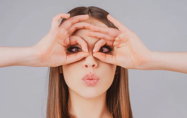 Emociones de gente loca. Chica bonita con la cara sorprendida sosteniendo los dedos cerca de los ojos como gafas. —  Fotos de Stock