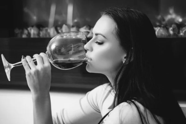 高級ワインだ。フランスワインをお楽しみください。レストランやワイナリー。豪華な女性はグルメワインを飲む。女の子魅力的な女性の化粧顔を飲むワイングラス背景暖炉の背景 — ストック写真